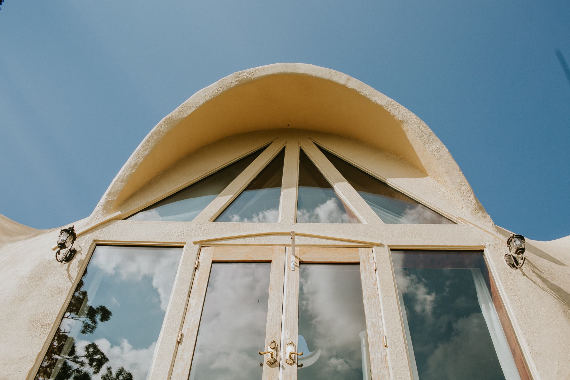 Looking up at a dome cathedral window against clouded blue sky